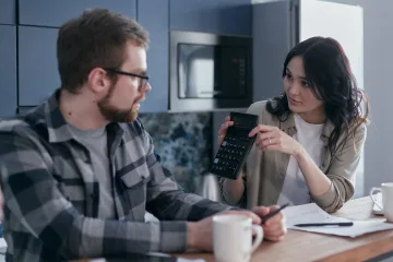 Vrouw laat een berekening op een rekenmachine aan een man zien als afbeelding bij een blog over AOW-franchise 2024